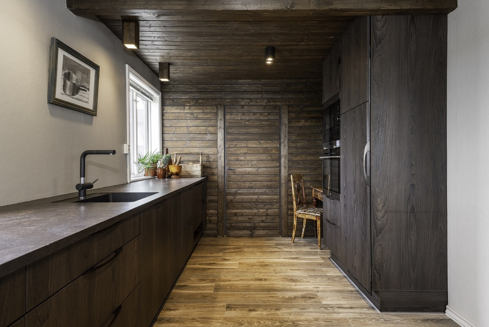 Treoverflatene skaper en lun og eksklusiv atmosfære. I bakkant finner du et stort lagringsrom, praktisk for ekstra kjøkkenredskaper og matlager. Galleribilde