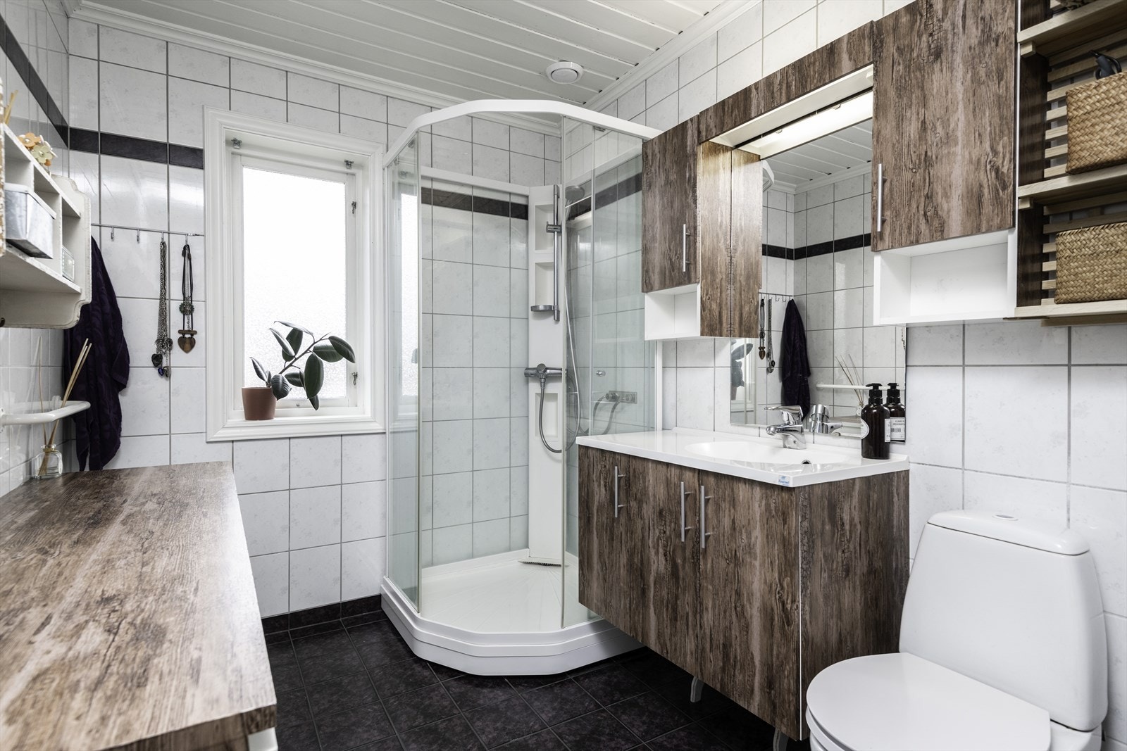 Badet i 1. etasje er utstyrt med servant med underskap. overskap, toalett og dusjkabinett. Galleribilde