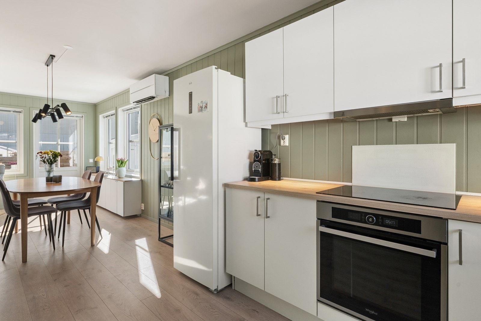 Kjøkkenet er praktisk utformet med slette, hvite fronter og integrert stekeovn og platetopp. Galleribilde