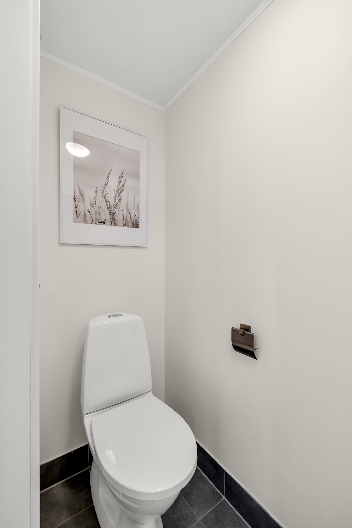Det er lagt fliser på gulv, malte vegger og tak, vegghengt servant og gulvstående toalett. Galleribilde