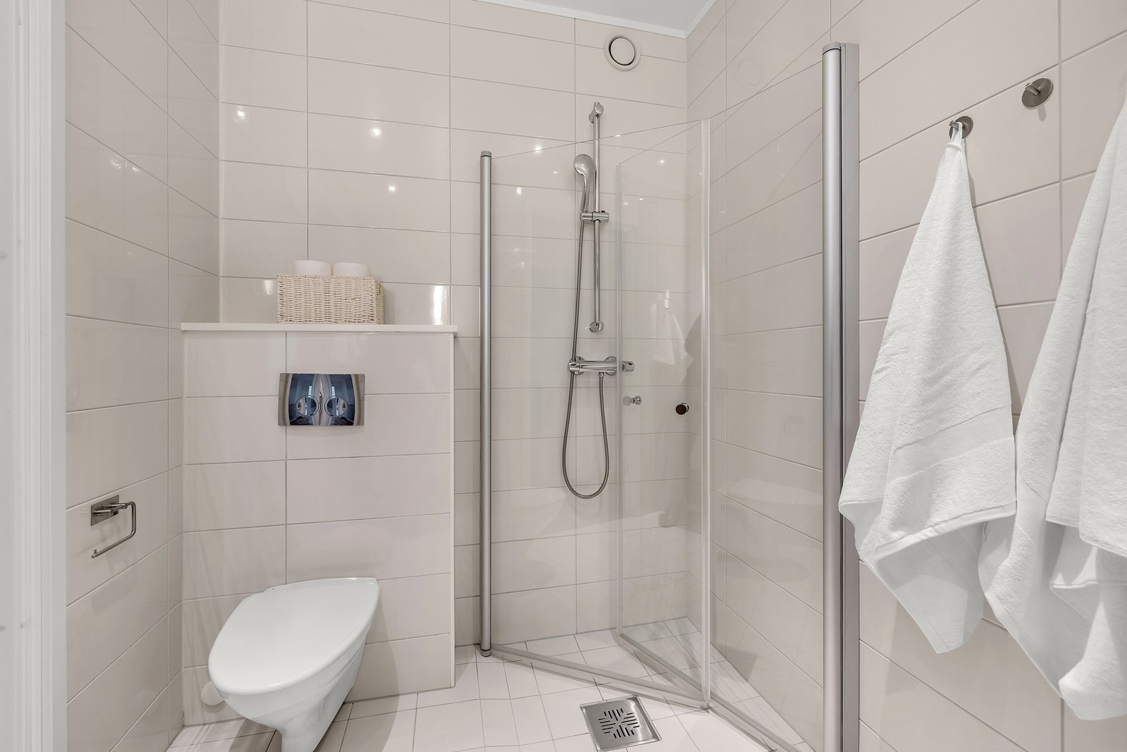 Badet har vegghengt toalett med innebygd sisterne kasse. Servant på vegghengt servantskap og vegghengte dusjdører i glass. Elektriske varmekabler i gulvet. Galleribilde