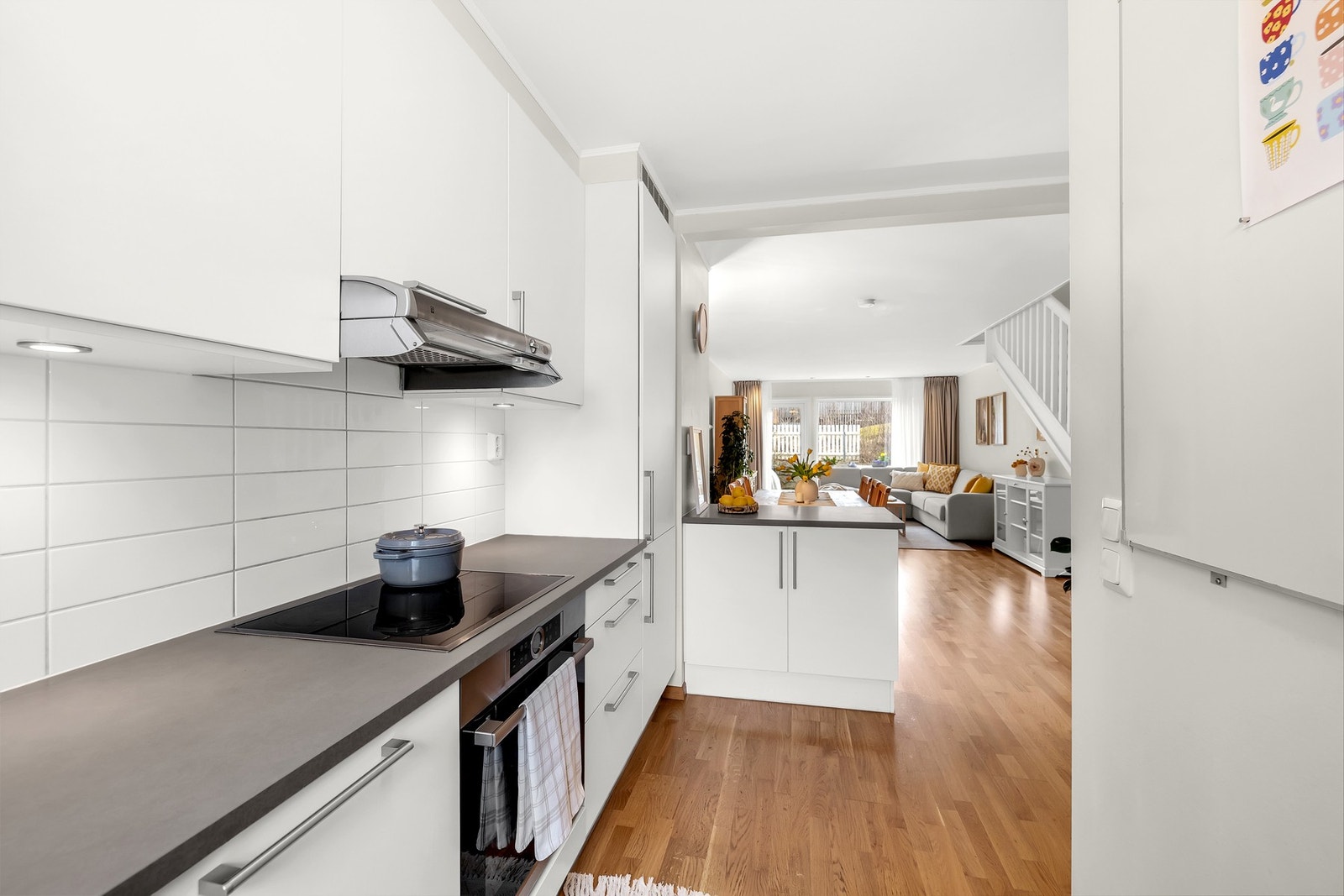 Kjøkken fra byggeår med glatte fronter, benkeplate i laminat og flislagt vegg over kjøkkenbenk.
Integrerte hvitevarer med platetopp, komfyr, oppvaskmaskin og
kjøl-frys. Galleribilde
