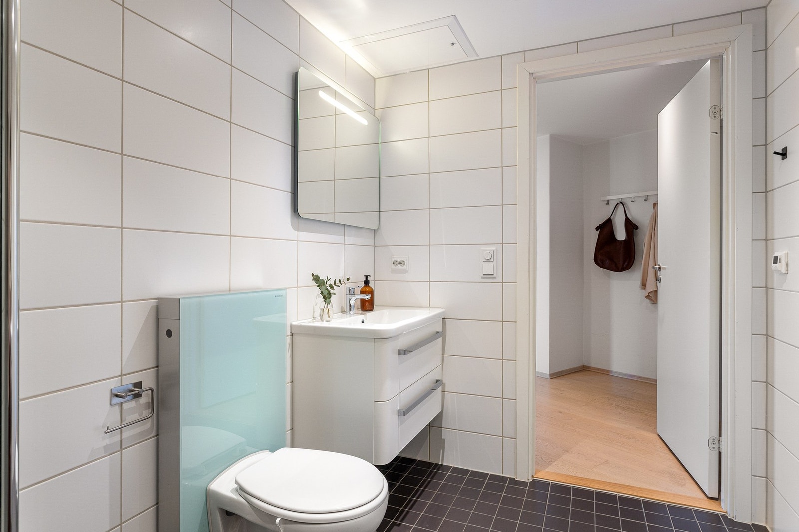 Videre er det vegghengt toalett og dusjhjørne med svingbare dører som frigjør plass på gulvet. Det er opplegg for vaskemaskin og mulighet for tørketrommel over. Galleribilde