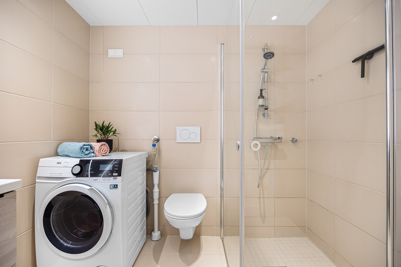 En moderne baderomsinnredning med heldekkende servant med underskuffer og speil med belysning. Galleribilde