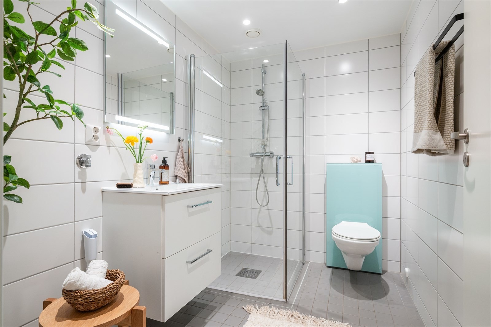 Pent og tidsriktig baderom fra byggeår. Badet er innredet med dusjhjørne med glassdører, vegghengt toalett og baderomsinnredning med skuffer for oppbevaring. Det er vegghengt speil samt opplegg for vaskemaskin og tørketrommel. Galleribilde