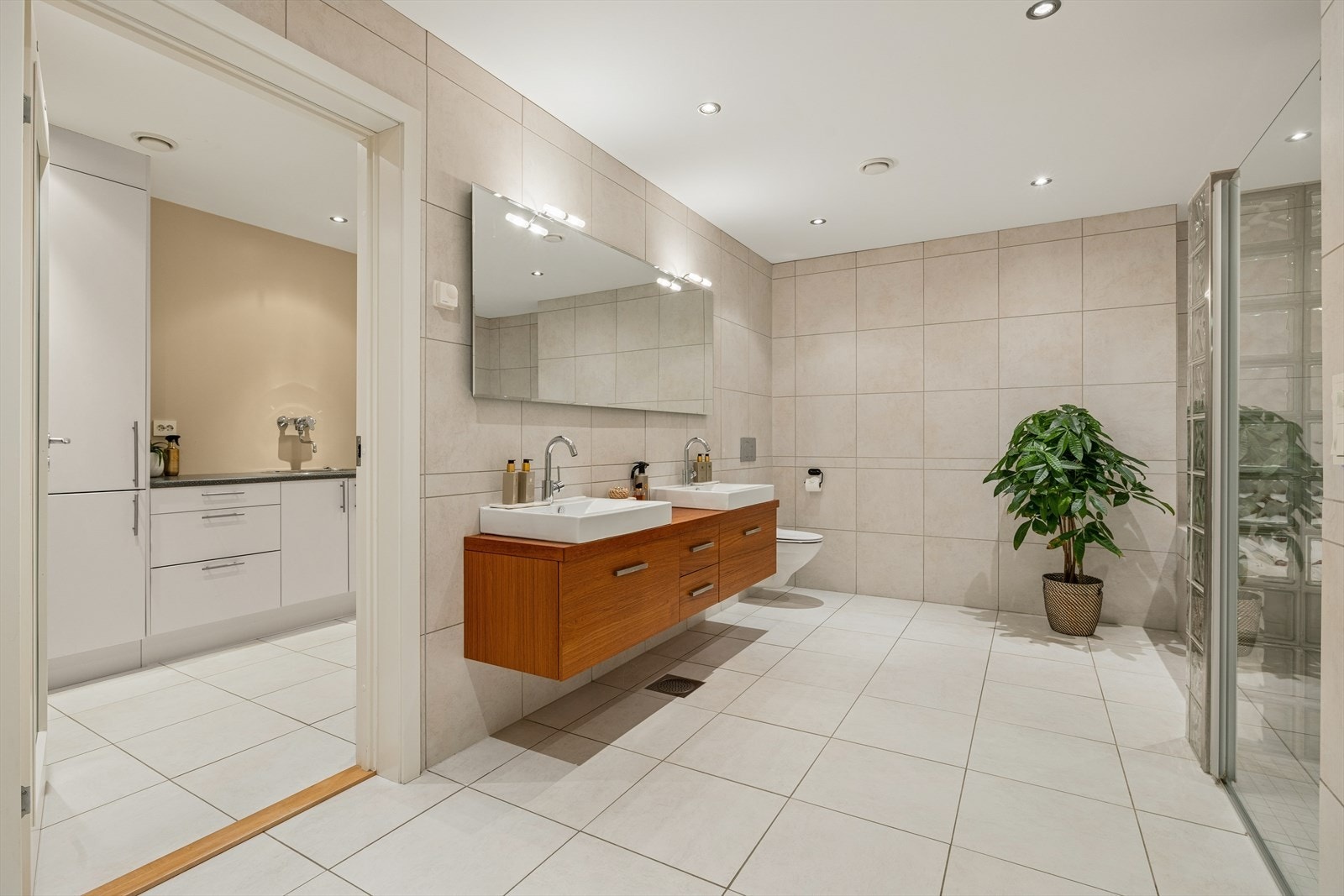 I underetasjen ligger boligens største bad - et lekkert, helfliset bad med dobbel servant, dusjhjørne, vegghengt toalett og et innfelt badekar. Galleribilde