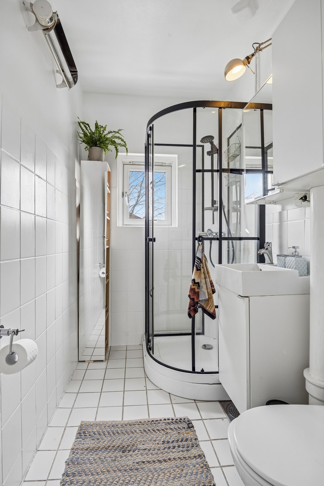 Badet har flislagt gulv, dusjkabinett og vegghengt servantskap. Ventilasjon skjer via avtrekksventil. Galleribilde