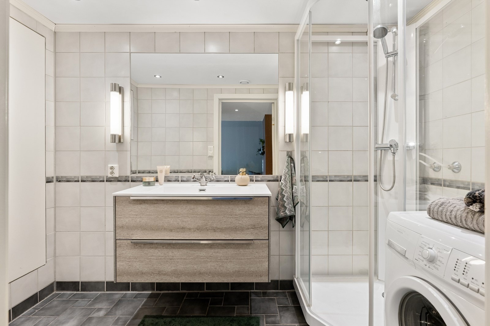 Tidløst baderom på ca. 4,5 kvm, med behagelig gulvvarme. Gode oppbevaringsløsninger med servant med skuffer og integrert skap. Galleribilde