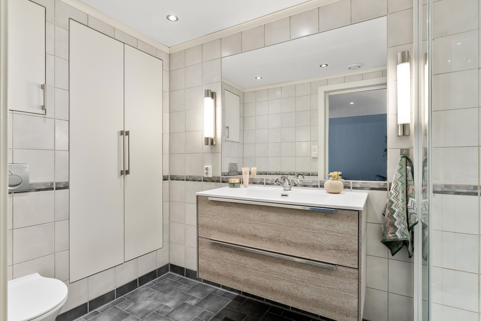 Badet er utstyrt med vegghengt toalett, speil, dusjkabinett og opplegg for vaskemaskin. Galleribilde