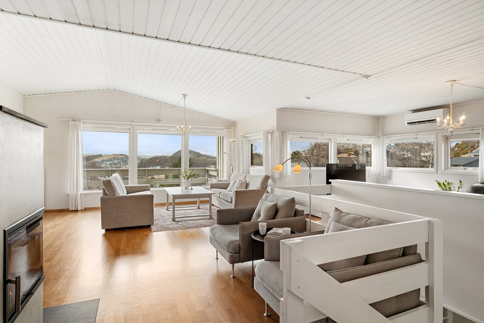 Flott stue med parkett på gulv og lyse vegger. Mye vinduer slipper inn naturlig lys. Galleribilde