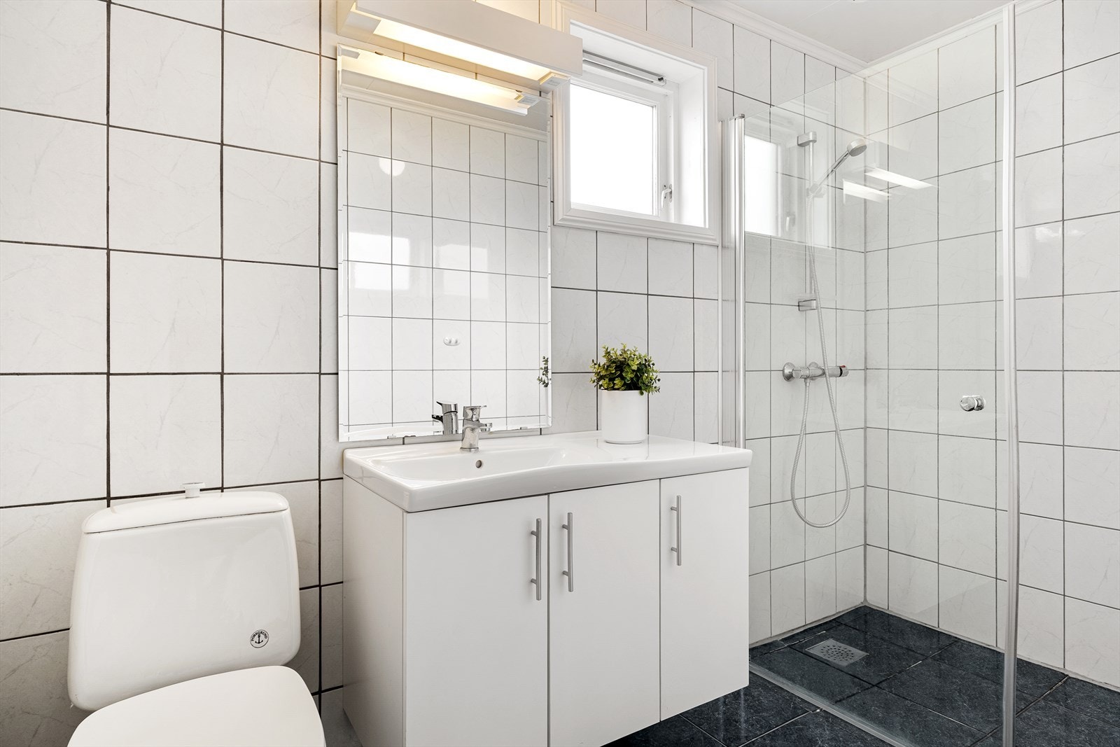 Helfliset bad med vask i seksjon, wc og dusjhjørne. Varmekabler i gulv. Galleribilde