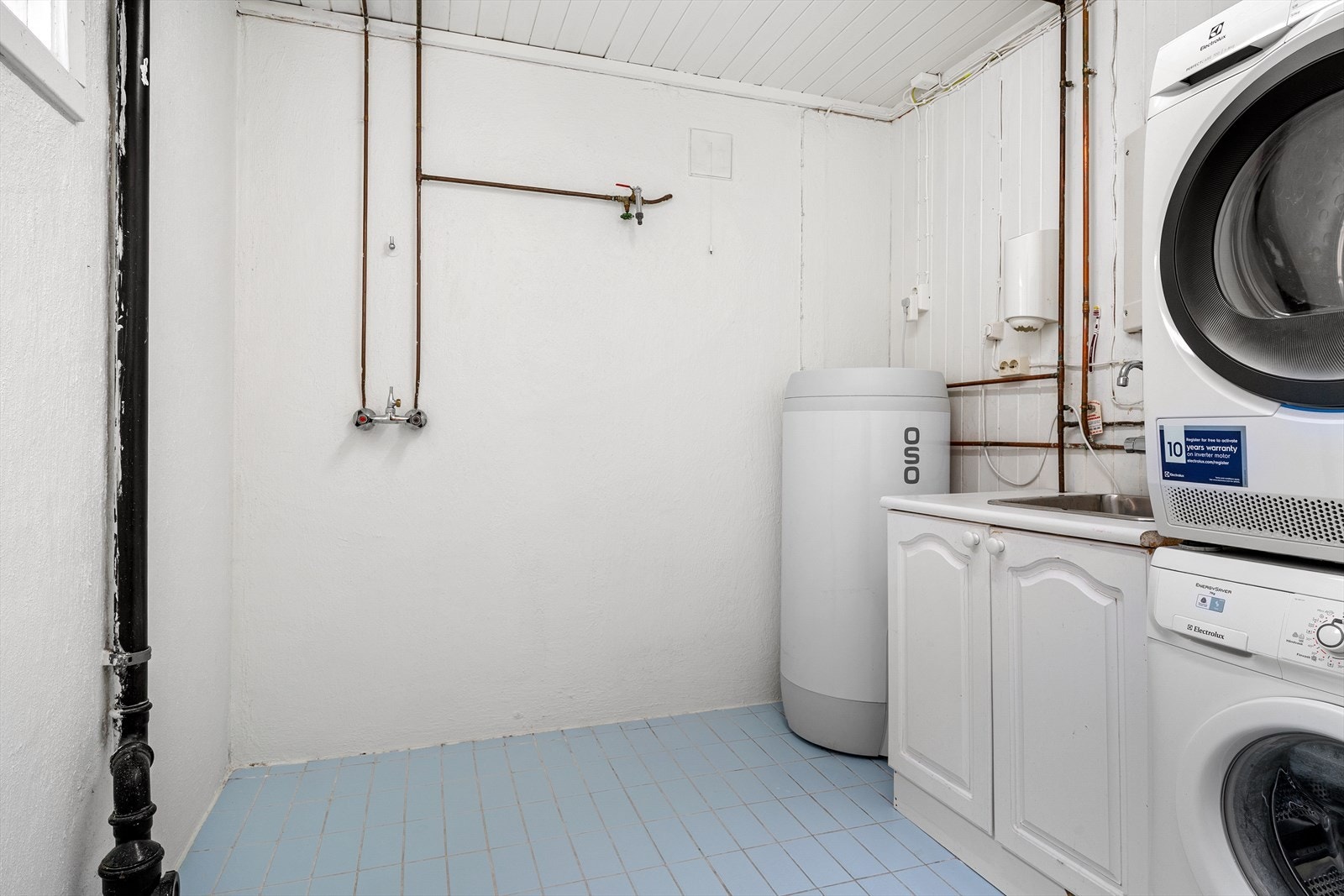 Vaskerom med fliser på gulv og utslagsvask. God plass til tørking av klær. Galleribilde