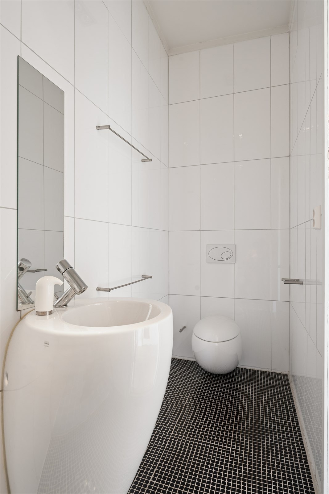 Badet er onnredet med servant med ett-greps blandebatteri, vegghengt toalett og dusj med glassvegg. Galleribilde