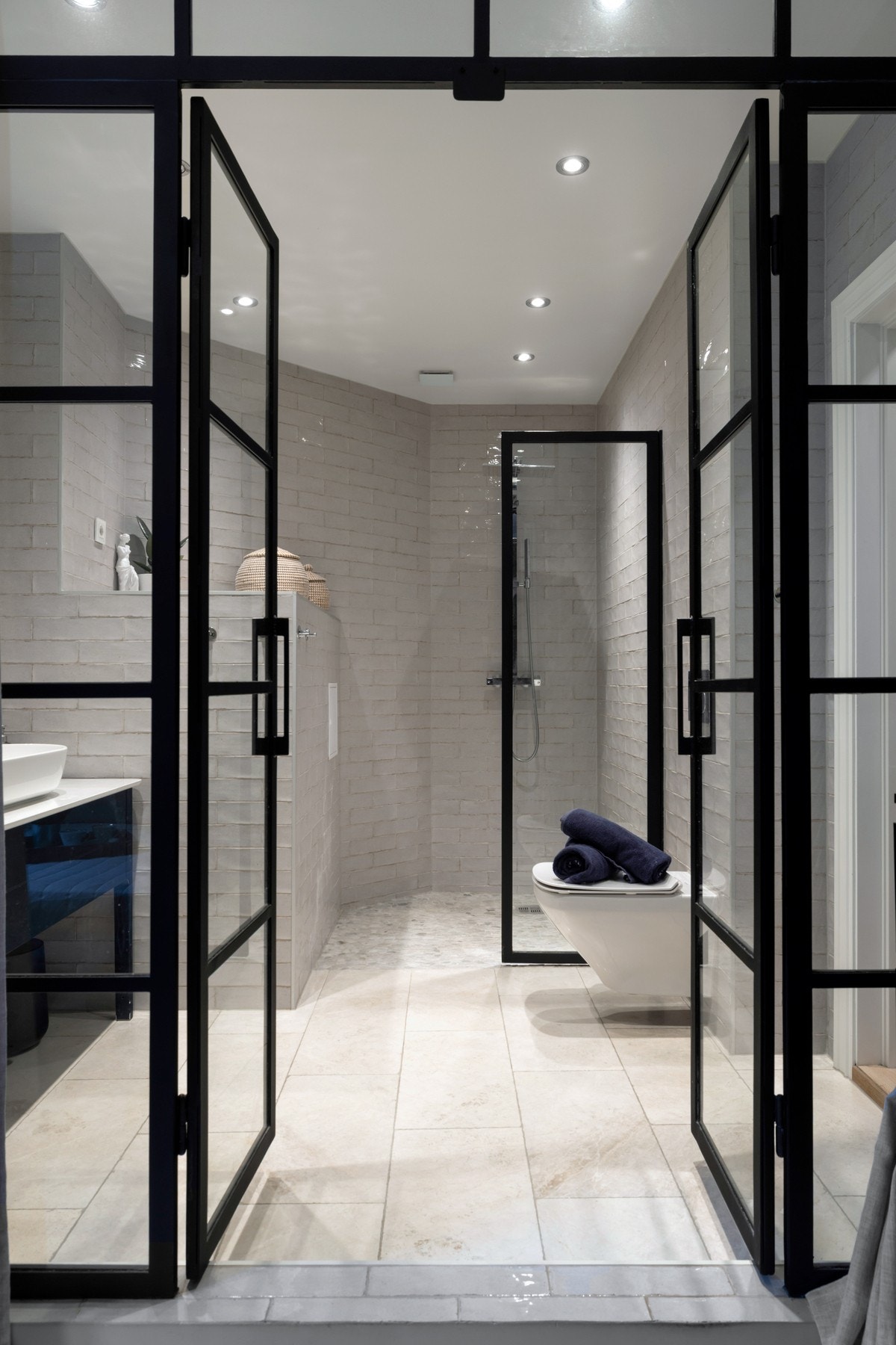 Badet er innredet med dusjnisje med glassvegg, vegghengt toalett og servant med tilhørende innredning. Galleribilde