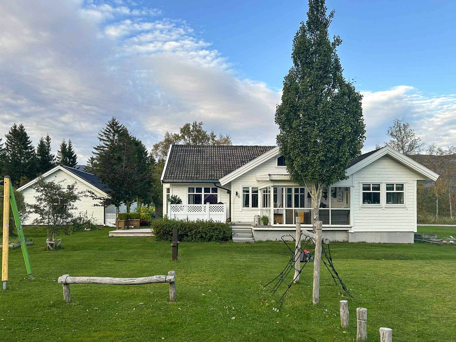 Pent opparbeidet og flat tomt med etablert lekeplass med naboeiendom. Galleribilde