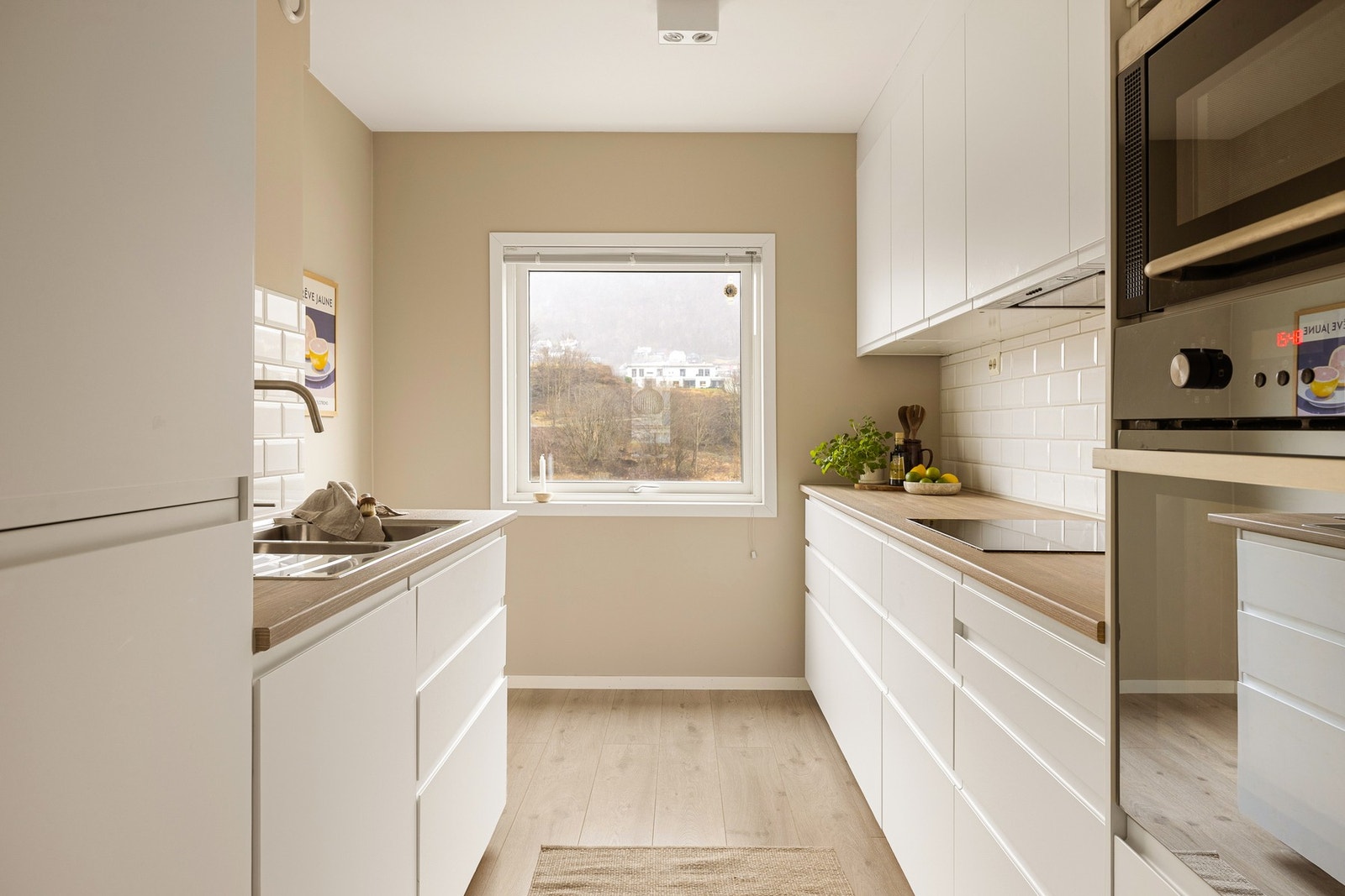 Kjøkkenet fremstår tidløst med lyse slette fronter og laminert benkeplate Galleribilde