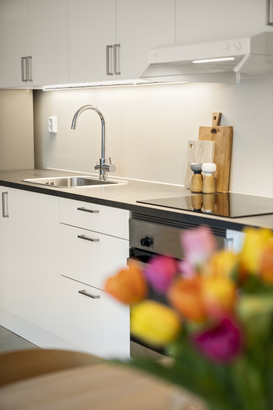 Kjøkkeninnredning fra HTH med glatte fronter og benkeplate av laminat. Nedfelt vask i rustfritt stål, kjøkkenarmatur og opplegg for oppvaskmaskin. Galleribilde