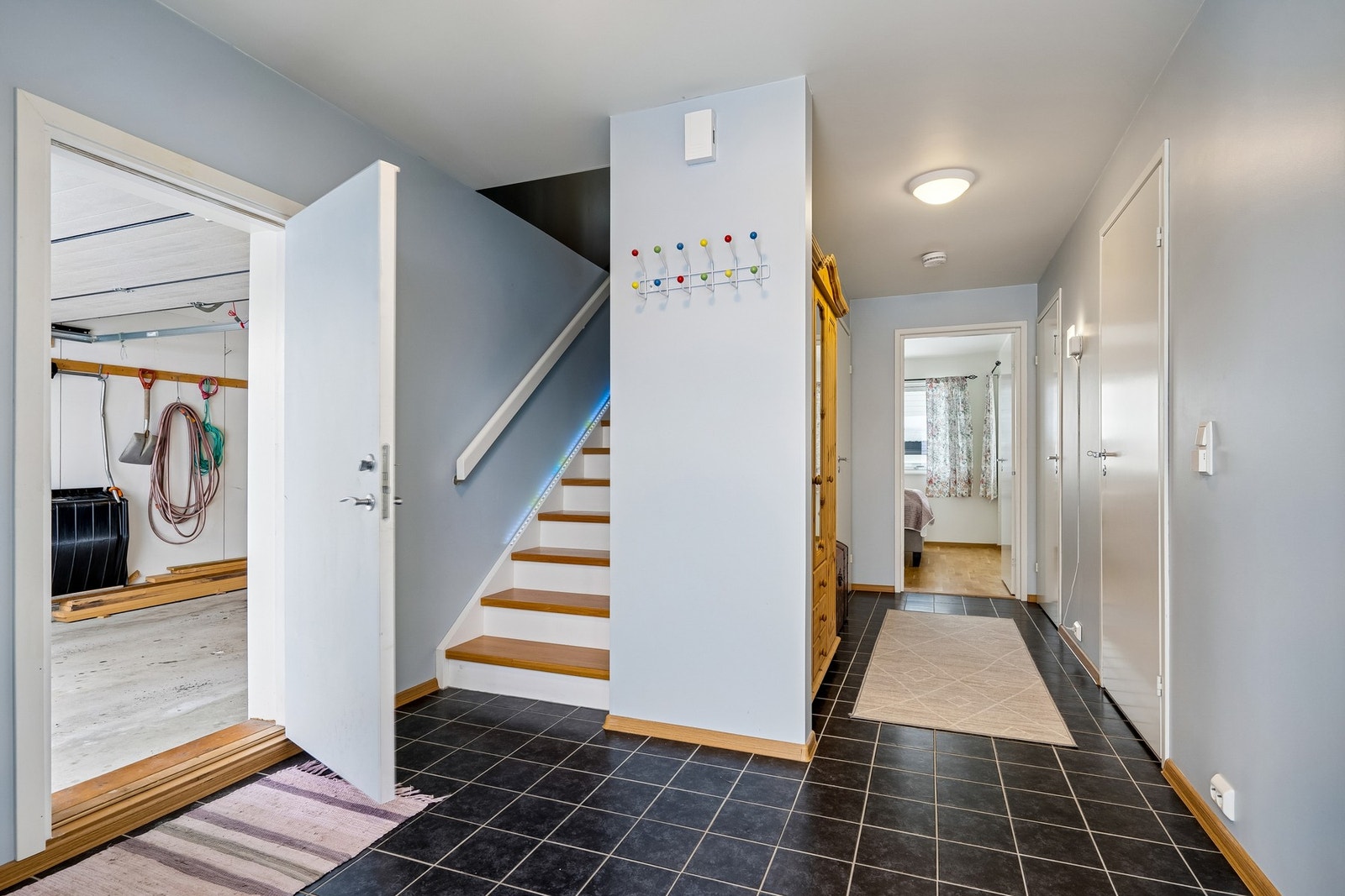 Flislagt hall med trapp, varmekabler og garderobeskap. Inngang direkte til garasjen. Galleribilde