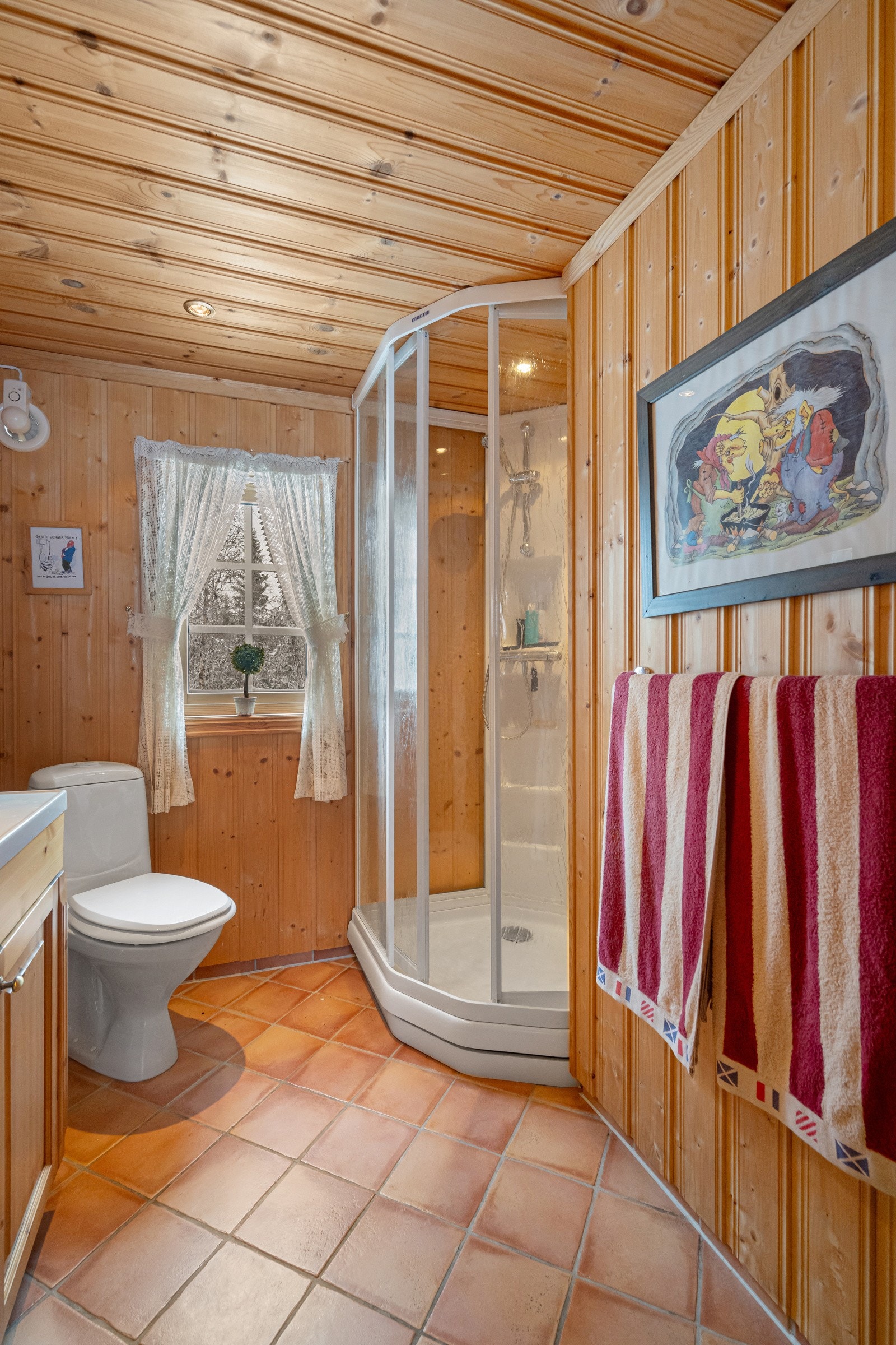 Veggene og himlingen er kledd med lakkert panel. Badet har praktisk innredning med en nedfelt servant, toalett og et dusjkabinett Galleribilde