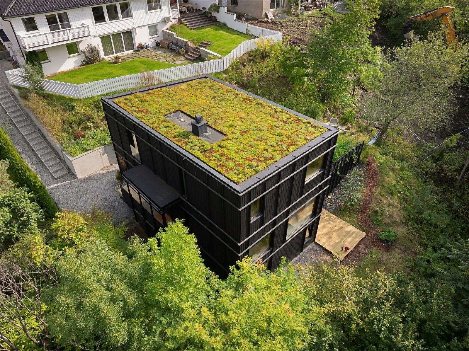 Opparbeidet og skrånende tomt på hovedsaklig to plan med gressplen, naturtomt og terrasser på begge plan Galleribilde