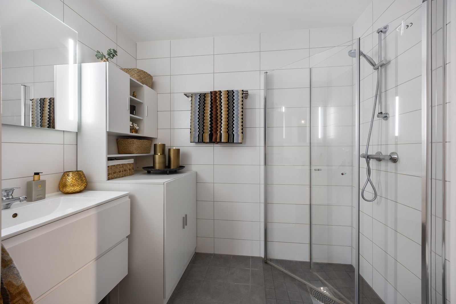 Opplegg for vaskemaskin er etablert, og badet har varmekabler, vegghengt toalett og et dusjhjørne med innfellbare dører. Galleribilde