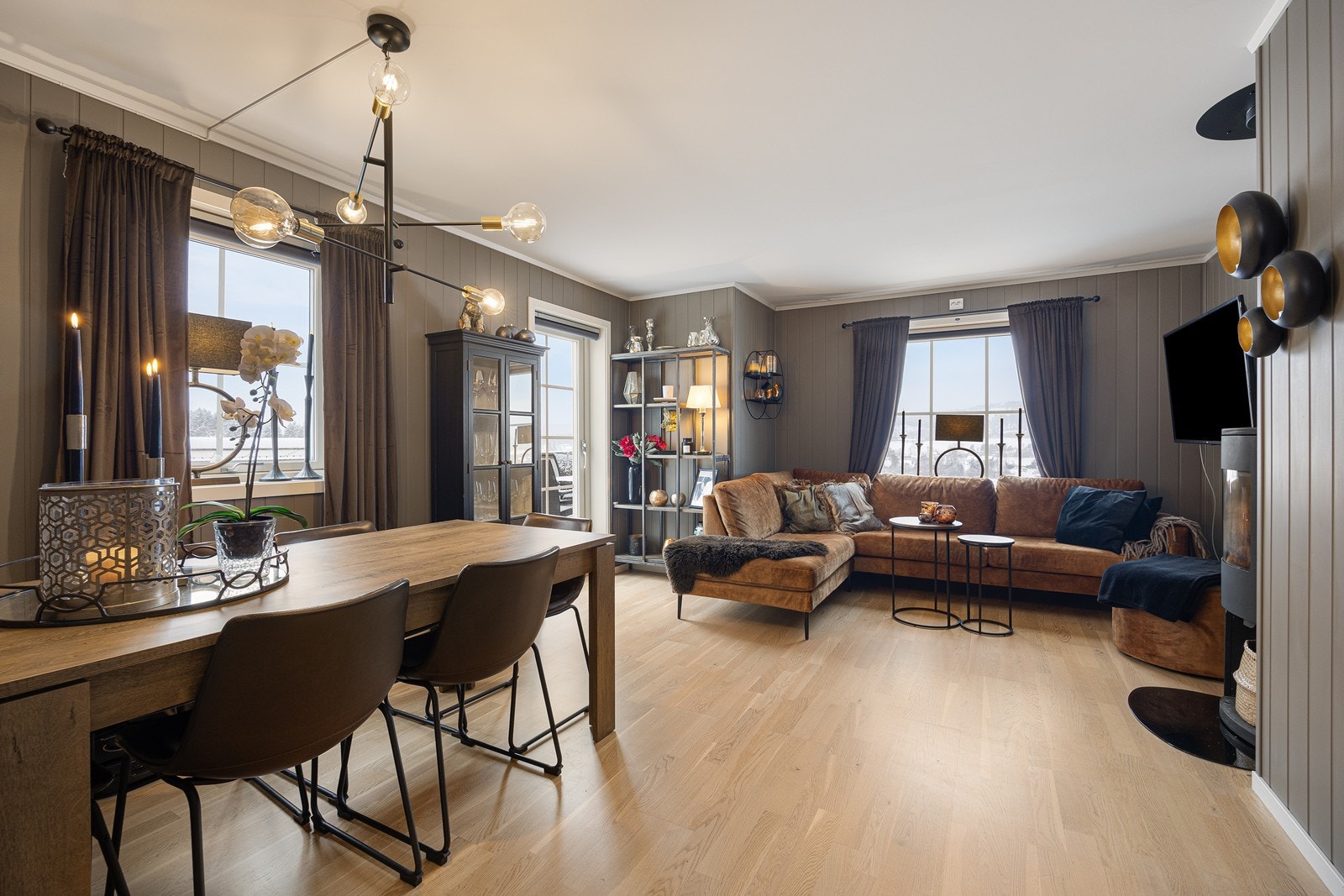 Parkett på gulvet kombineres med brunmalte panelplater, og utformingen gjør stuen enkel å møblere med en sofagruppe i tillegg til et langbord. Galleribilde