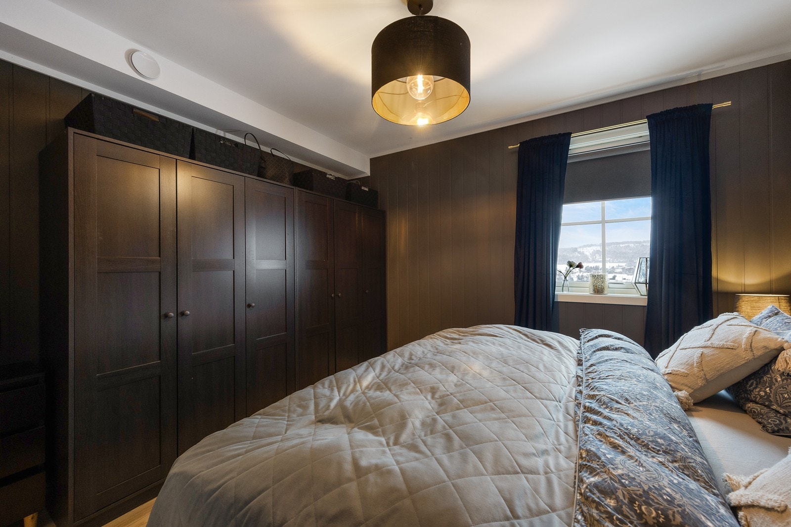 Det er mye oppbevaring i et stort garderobeskap med mørke, profilerte fronter. Galleribilde