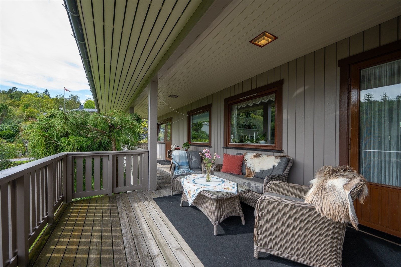 En overbygget og fin veranda med utgang fra stue og ett soverom, trapp på enden med nedgang til hagen. Galleribilde