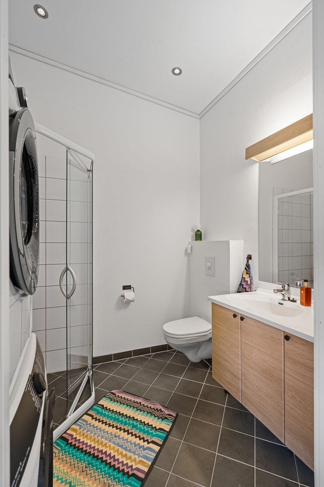 Innredning med vask/underskap m/speil, vegghengt toalett og dusjhjørne. Galleribilde