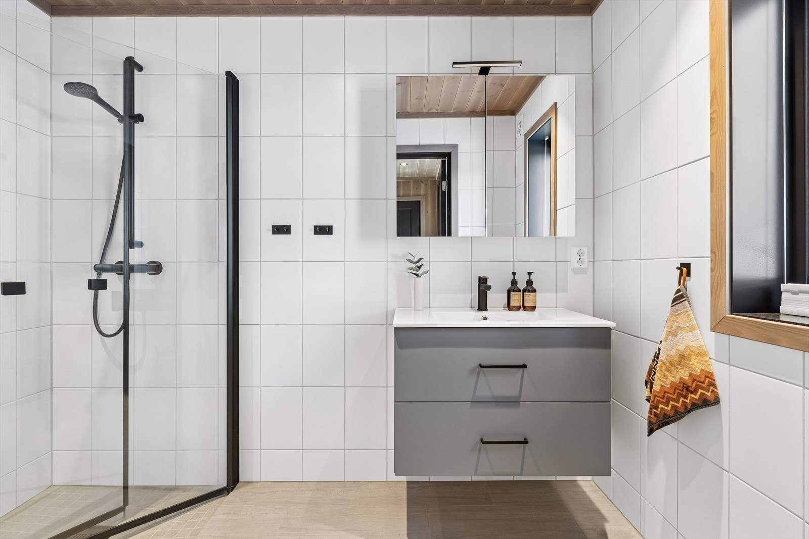 Badet har flislagte overflater og elektriske varmekabler i gulv. Innredning med nedfelt servant, innfellbare dusjdører og avtrekksvifte som sikrer god ventilasjon. Galleribilde