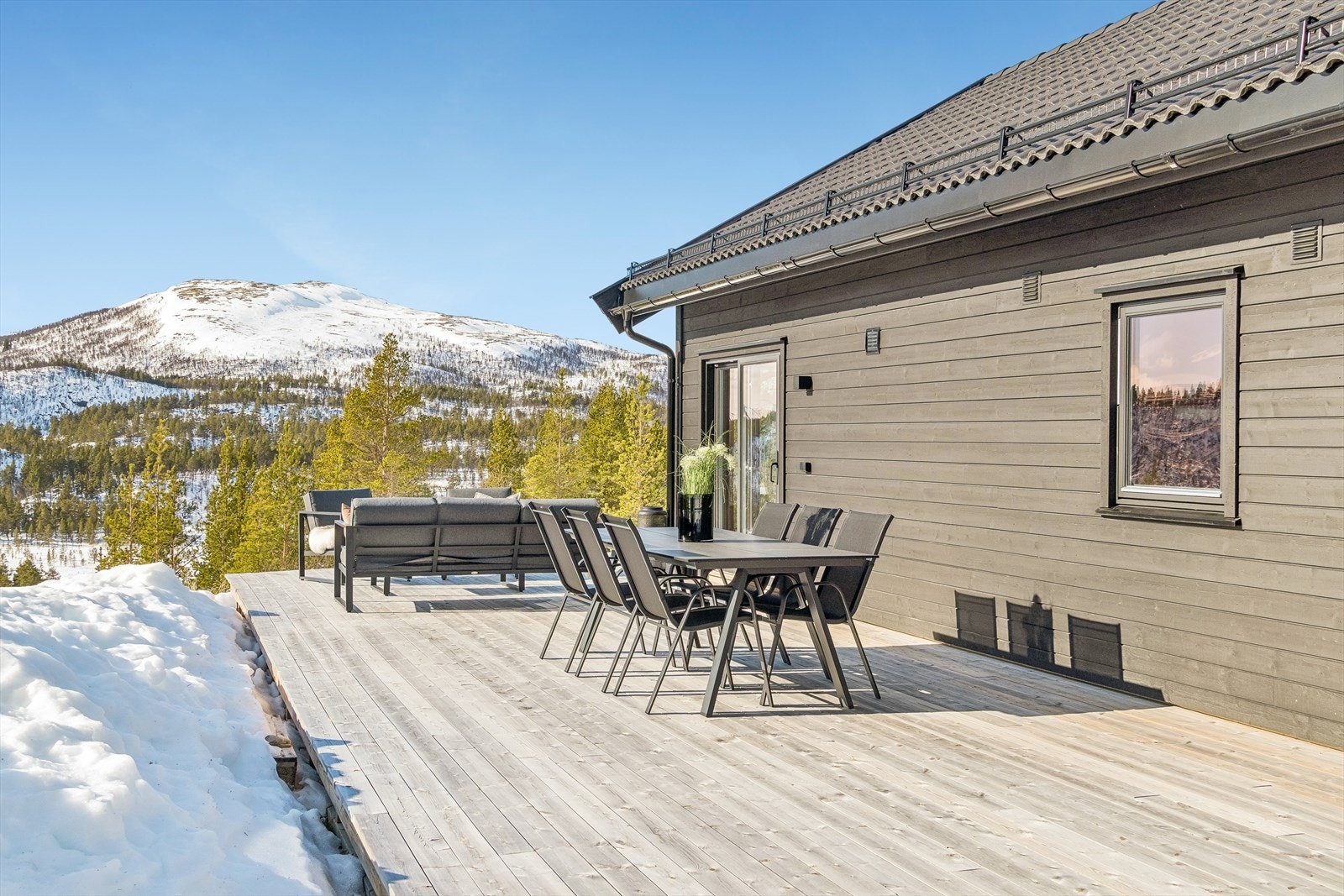 Fra terrassen er det en bred skyvedør i glass som åpner opp og trekker uteområdet inn i hytta. Galleribilde