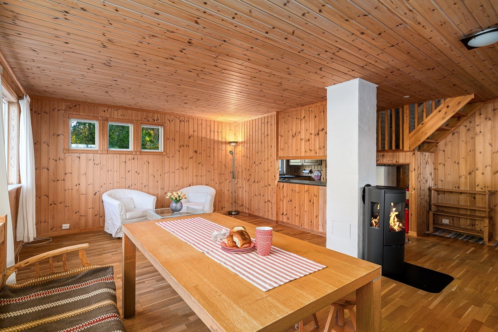 Fra spisestuen ser man den sentralt plasserte vedovnen og den lakkerte tretrappen som leder opp til loftsetasjen. Galleribilde