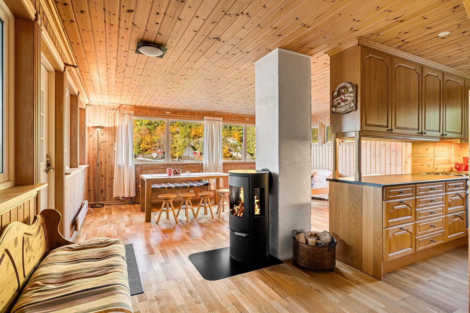 Hyttas hjerte er den åpne stuen og kjøkkenet, med gjennomgående trepanel på vegger og i tak. Galleribilde