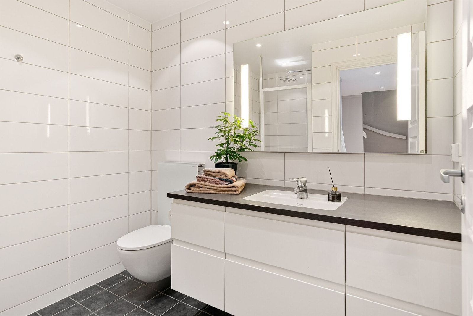 Pent flislagt bad i 1.etasje med kvaliteter som innredning fra HTH, rikelig med oppbevaringsplass, regndusj og downlights i himling. Galleribilde