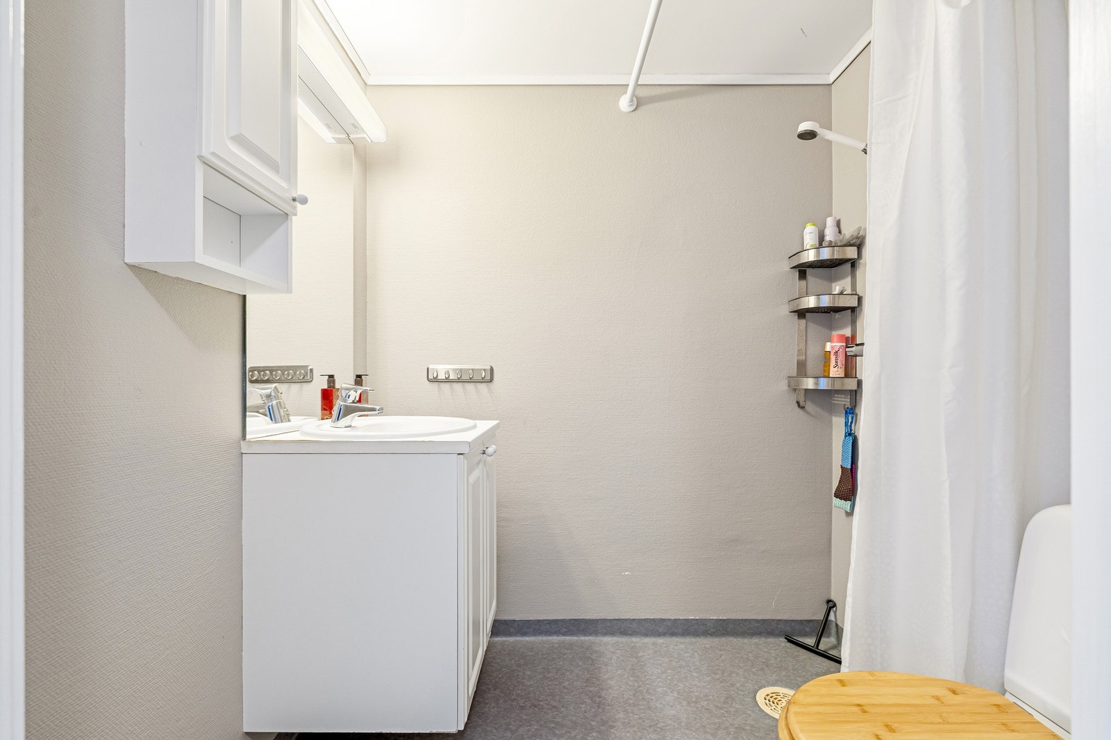 Funksjonelt bad med dusjhjørne og plassbesparende servantskap. Galleribilde