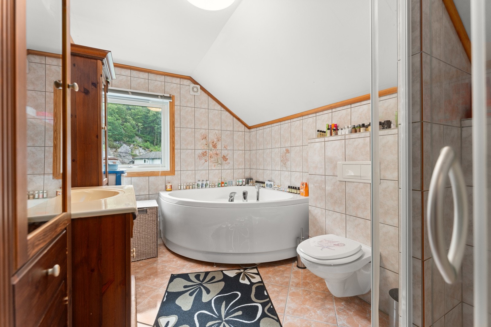 Pent flislagt bad med varmekabler i gulv, vegghengt toalett, hjørnebadekar og dusjhjørne. Galleribilde