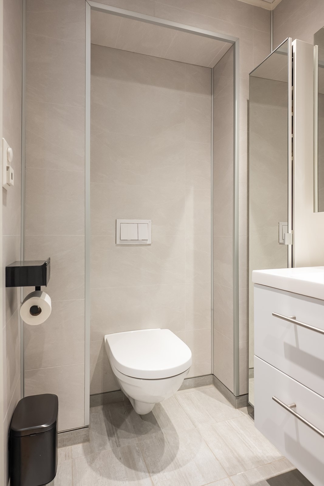 Videre er badet utstyrt med innfellbare dusjdører, baderomsinnredning, vegghengt klosett og opplegg for vaskemaskin. Galleribilde