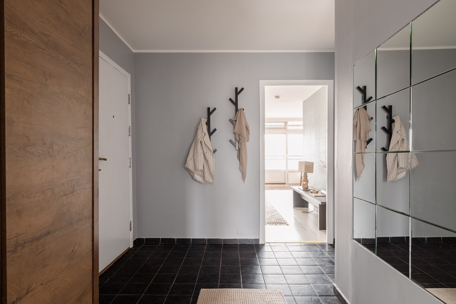 Hallen har flislagt gulv og leder videre inn mot stuen og leilighetens sosiale sone. Galleribilde