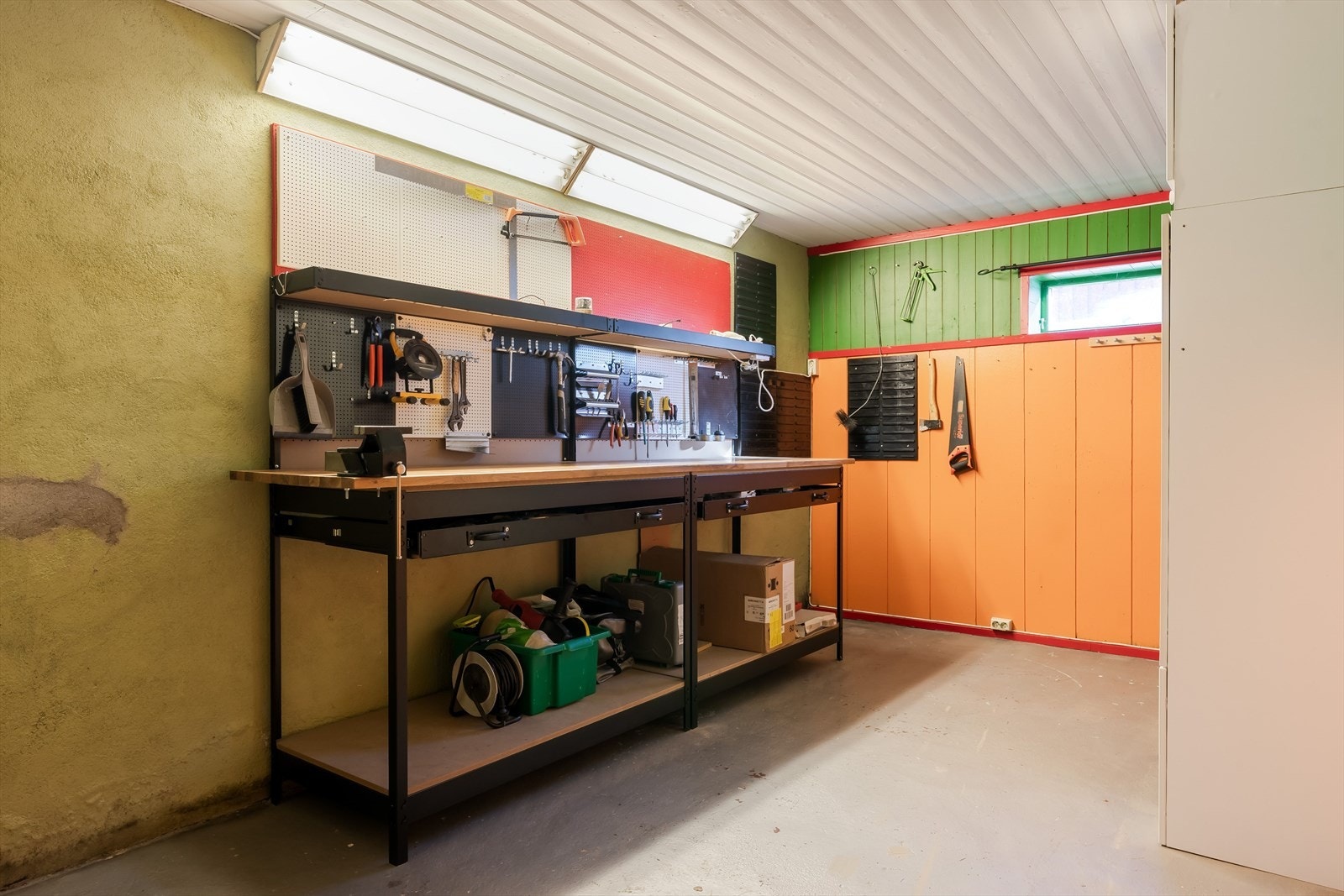 Verkstedet har en robust arbeidsbenk med god oppbevaringsplass under, ideelt for verktøy og utstyr. Galleribilde