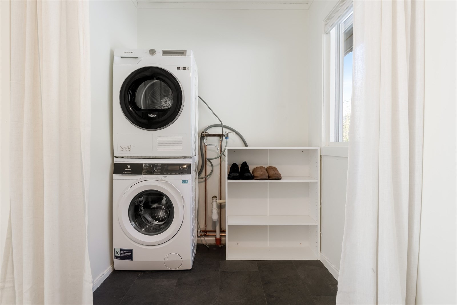 Vaskerommet har panel på vegger og pusset murverk, med grovstøpt betonggulv uten fall mot sluk. Rommet mangler membran og tettesjikt, noe som kan medføre behov for oppgradering. Galleribilde