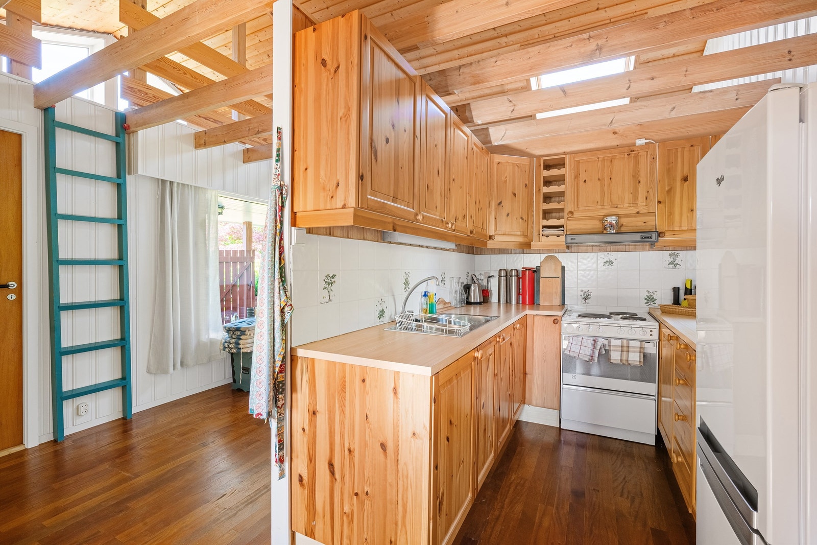 Kjøkkeninnredning i tre med god skap- og benkeplass. En praktisk hems over gir ekstra lagrings- eller soveplass. Galleribilde