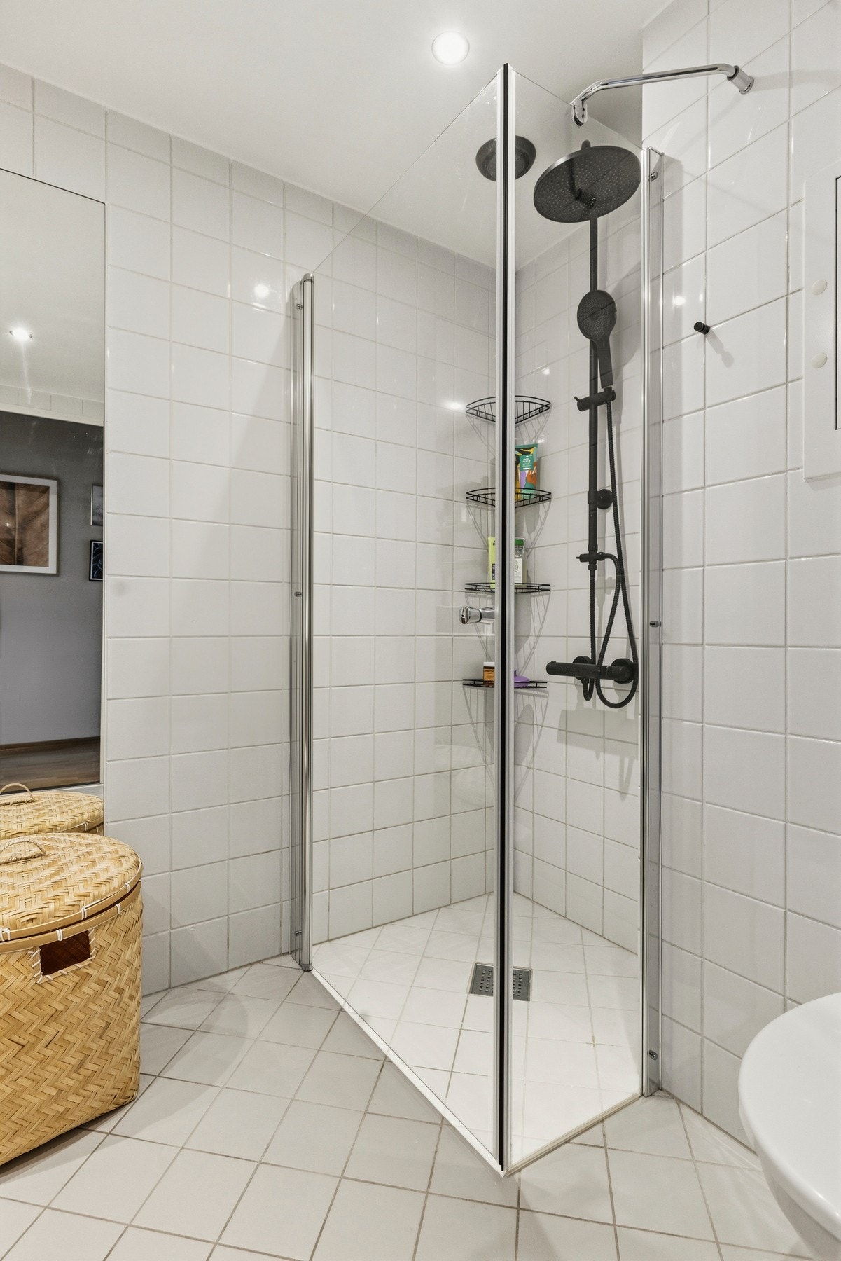 Ellers har rommet et veggmontert toalett og dusjvegger/hjørne med en svingbar glassdør Galleribilde