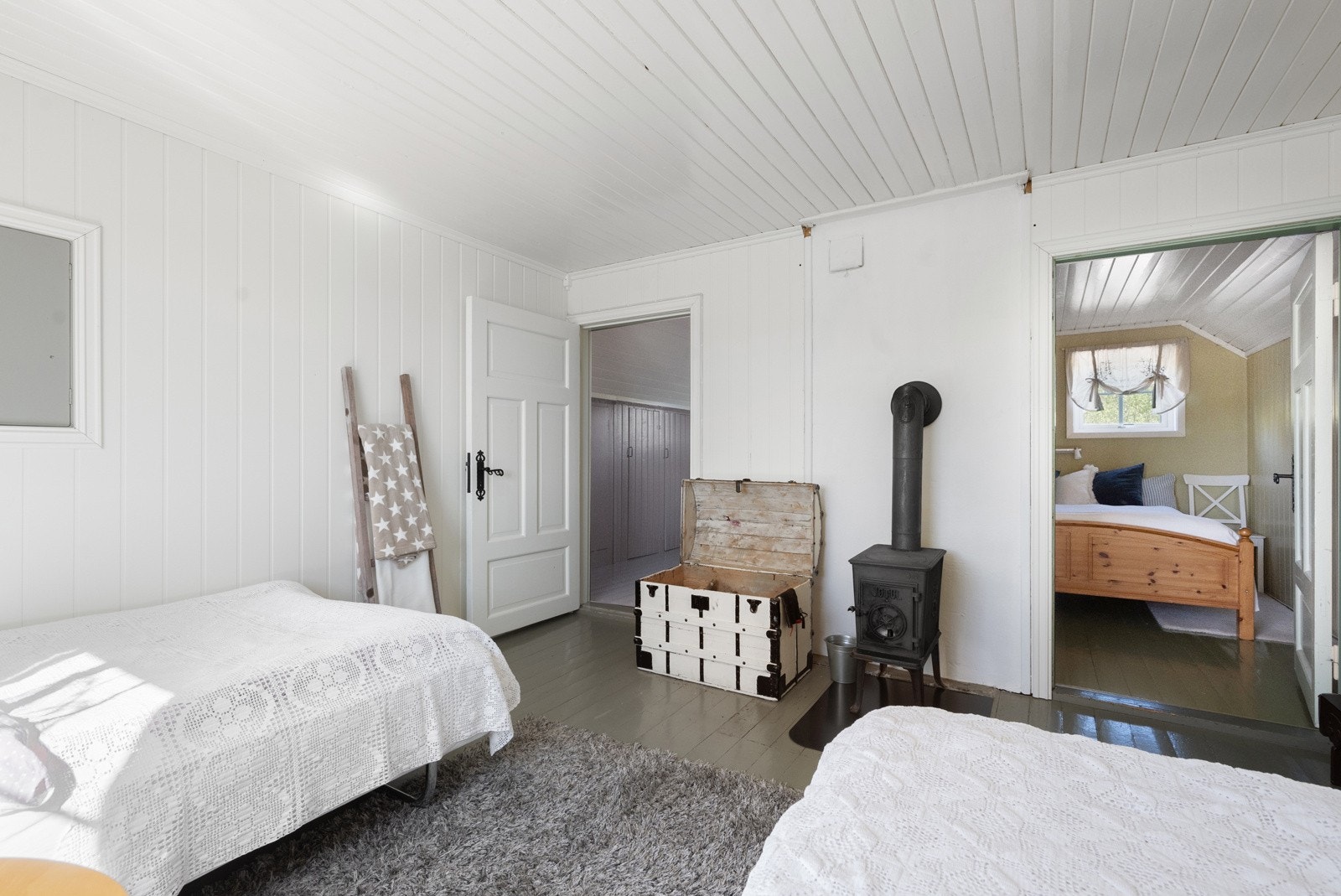 Romslig og sjarmerende soverom med en liten vedovn som gir ekstra varme og kos Galleribilde