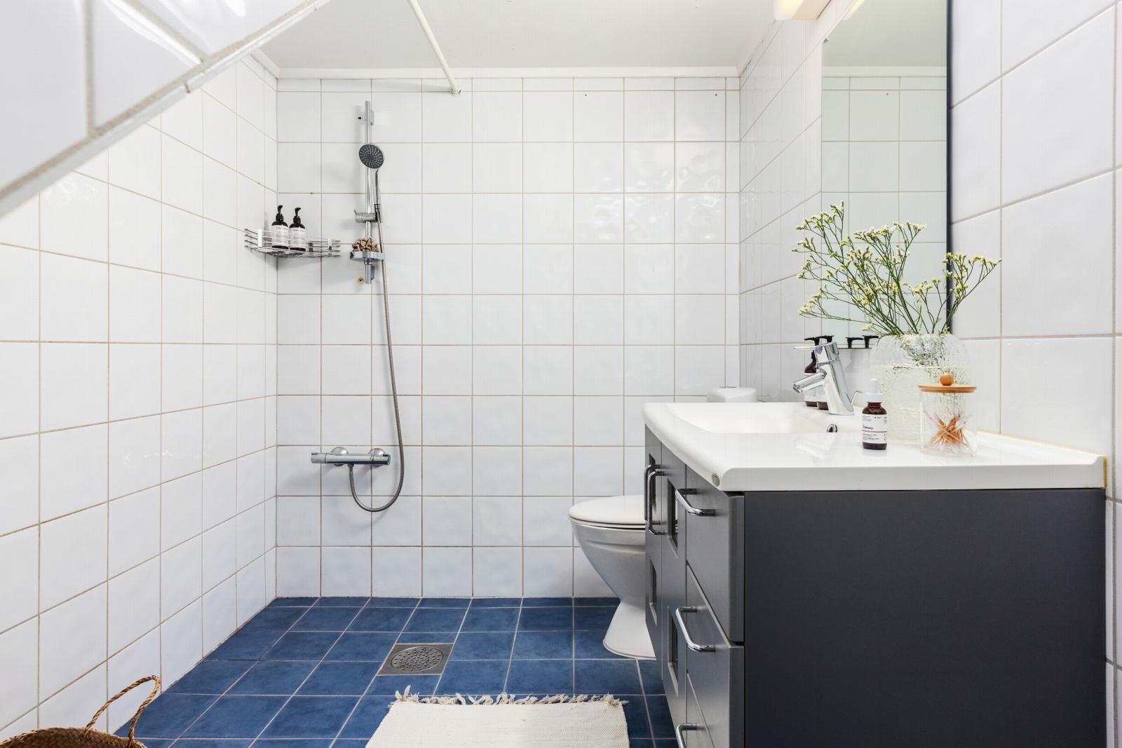 Bad med dusj, toalett og servant. Flislagt gulv og vegger. Praktisk innredning med skapplass. Galleribilde