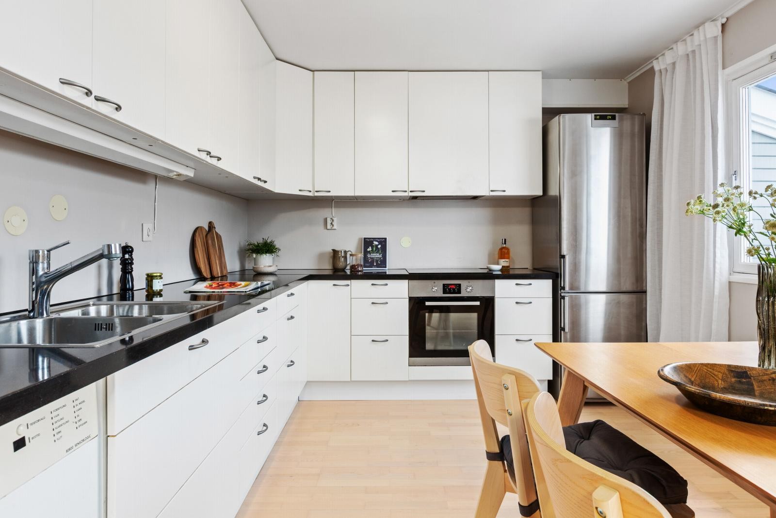 Takhøye skap på kjøkken med hvite skapfronter, integrerte hvitevarer og god benkeplass. Lys atmosfære med mye naturlig dagslys. noe bruksslitasje på frontene. Galleribilde