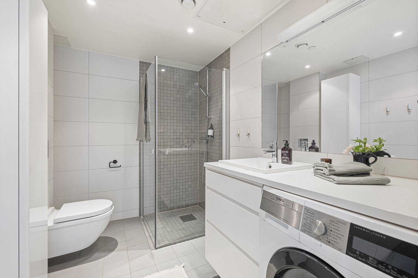 Romslig og moderne bad med flislagte overflater, downlights i taket og termostatstyrte varmekabler i gulvet. Galleribilde