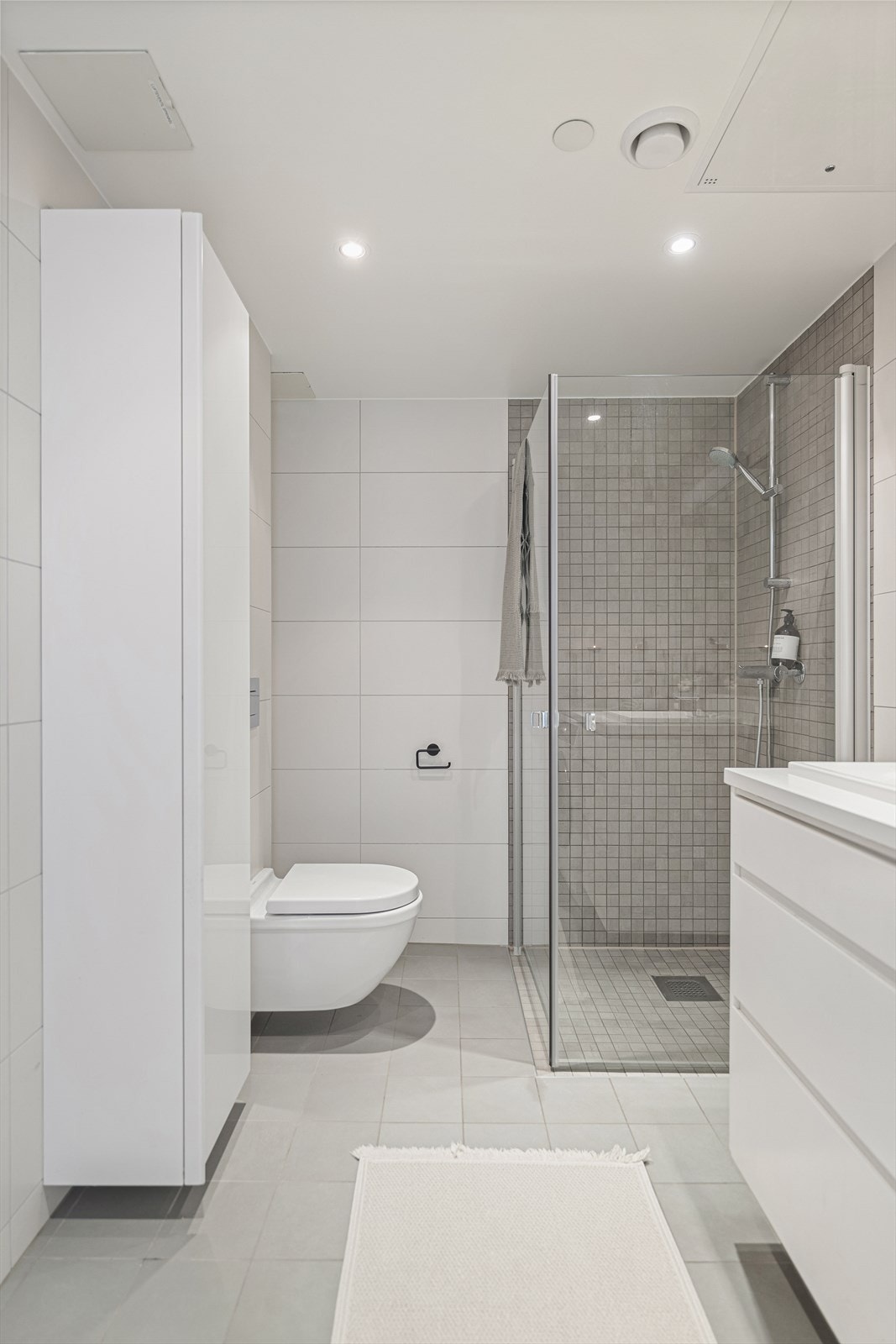 Badet er utstyrt med vegghengt toalett, dusjhjørne med svingbare glassdører og opplegg for vaskemaskin. Galleribilde