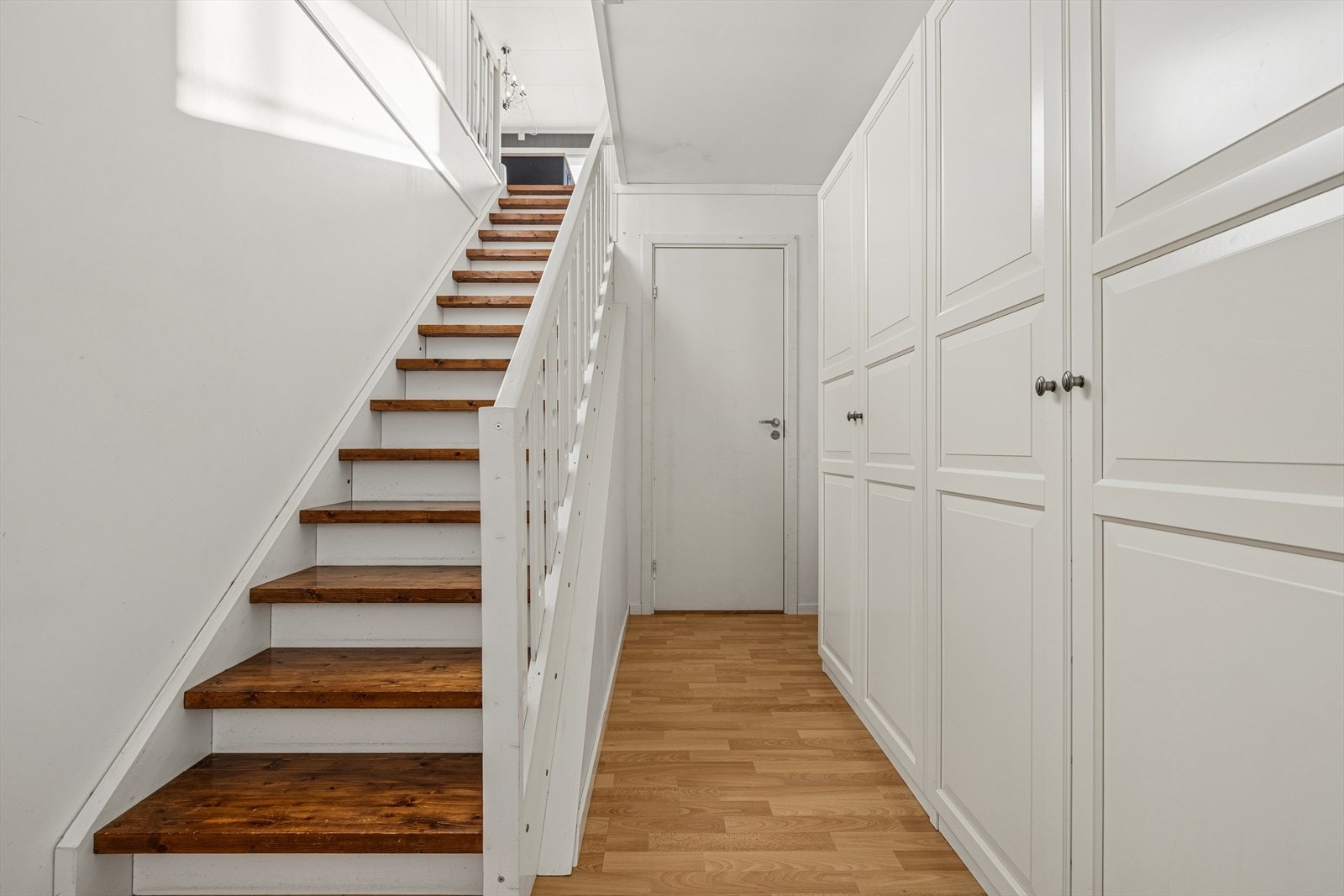 Stor og romslig gang med skapinnredning. Det er etablert dør fra gangen til stuen i underetasjen som skilte av hybeldelen. Galleribilde