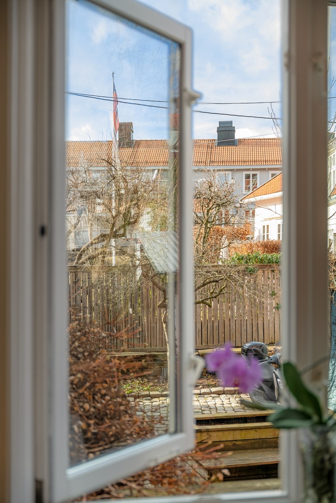 Utsikt fra kjøkkenvinduet mot et hyggelig og grønt gårdsrom. Galleribilde