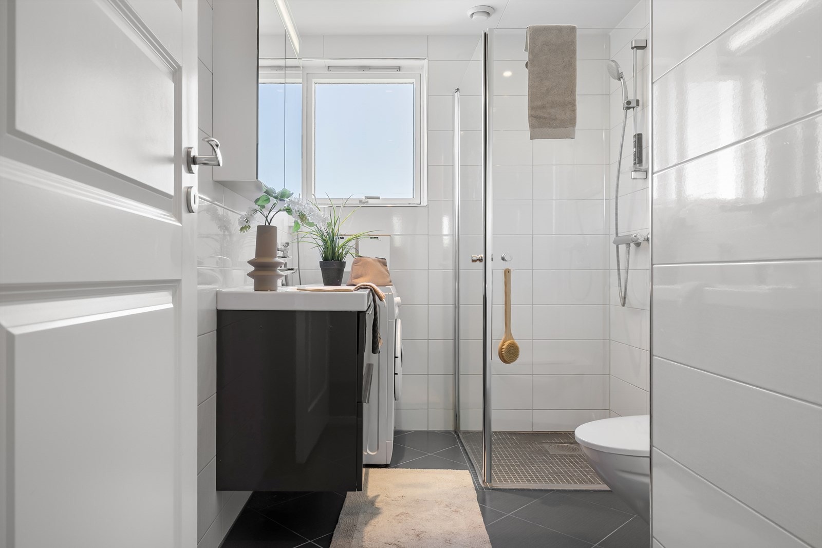 - Lyst bad innredet med toalett, dusjhjørne, servant med skuffer og speil med oppbevaring - Galleribilde